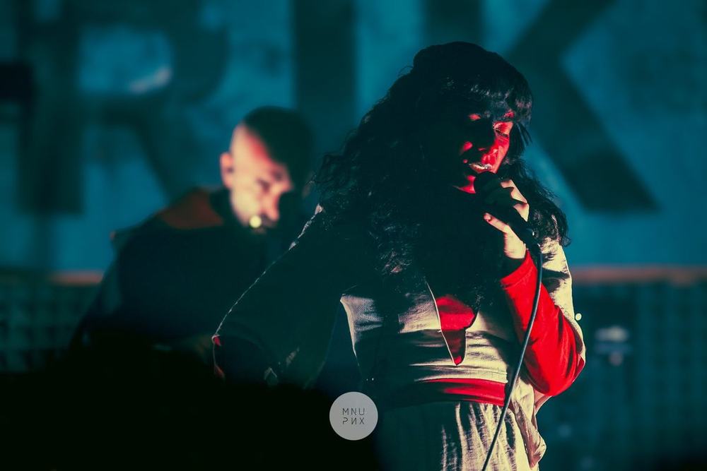 Dalila Kayros canta al microfono in luce rossa, Danilo Casti alle macchine sul fondo