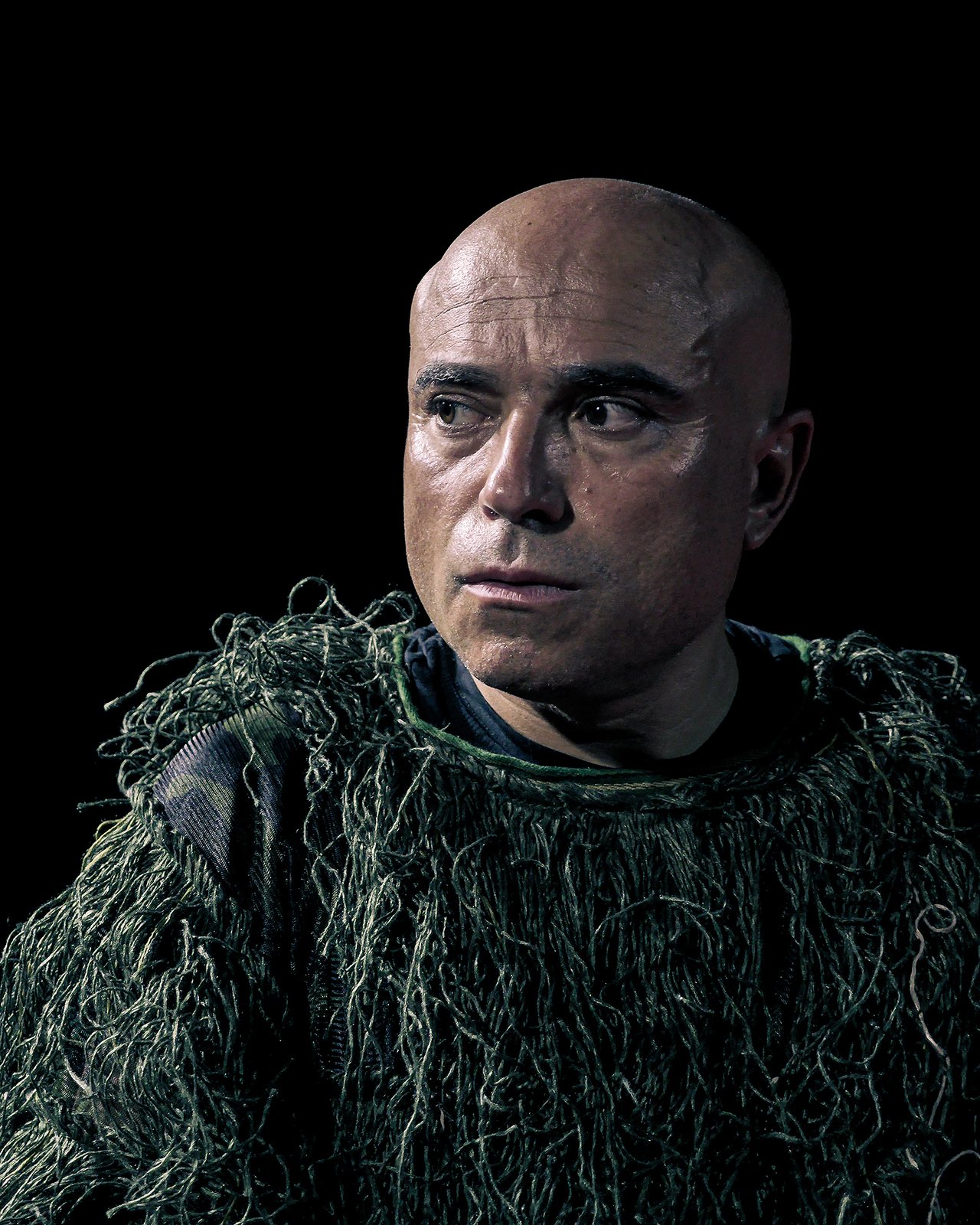Portrait of the performer with green fibres draped over his shoulders